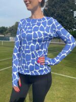 Female tennis player wearing a Pokita base layer, style cornflower giraffe.